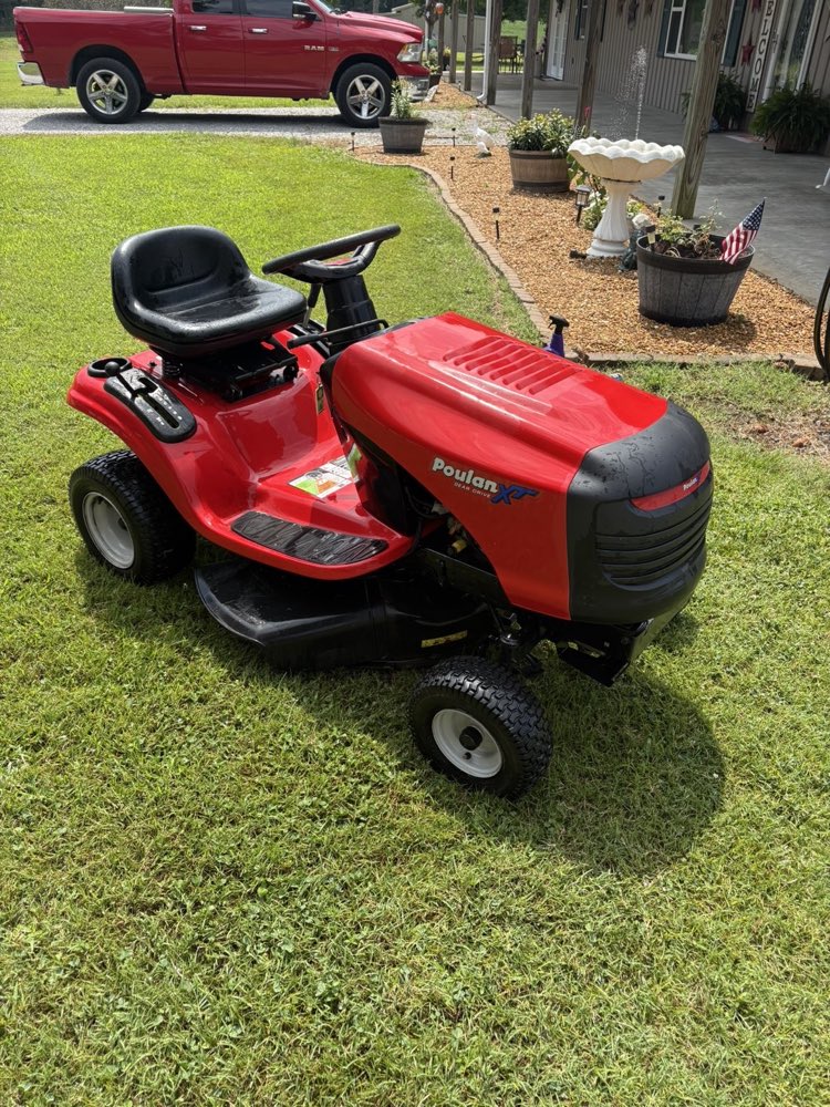A red Poulan XT riding mower, cleaned up and ready to sell, on a green lawn